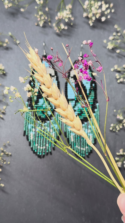 Long handmade beaded earrings in black, green, blue and beige featuring a raven and moon design with fringe. Boho statement jewelry, unique gift for her video 1